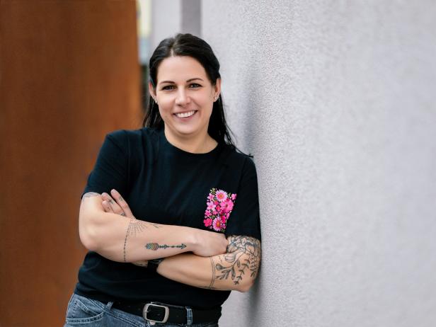 Hebamme Bettina Mayer aus Tulln lehnt an einer Wand und schaut in die Kamera