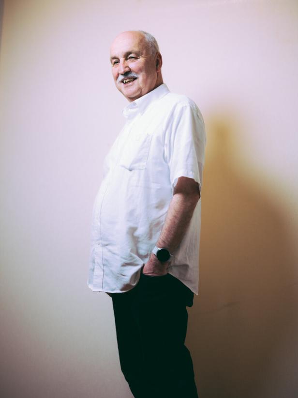 Der Theologe Wolfgang Palaver in weißem Hemd, blickt seitlich stehend, Hand in der Hosentasche, lächelnd zur Kamera 
