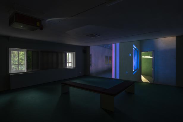 Dunkler Museumsraum mit Videobildern 