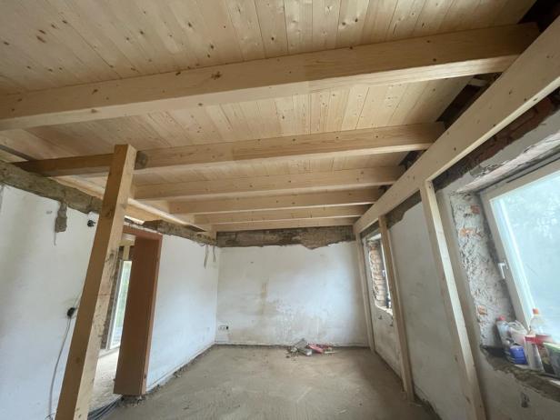 Ein renovierter Raum mit neuer Holzdecke und sichtbaren Holzbalken zeigt den Fortschritt eines Bauprojekts, wie es über die Plattform Daibau vermittelt werden kann.