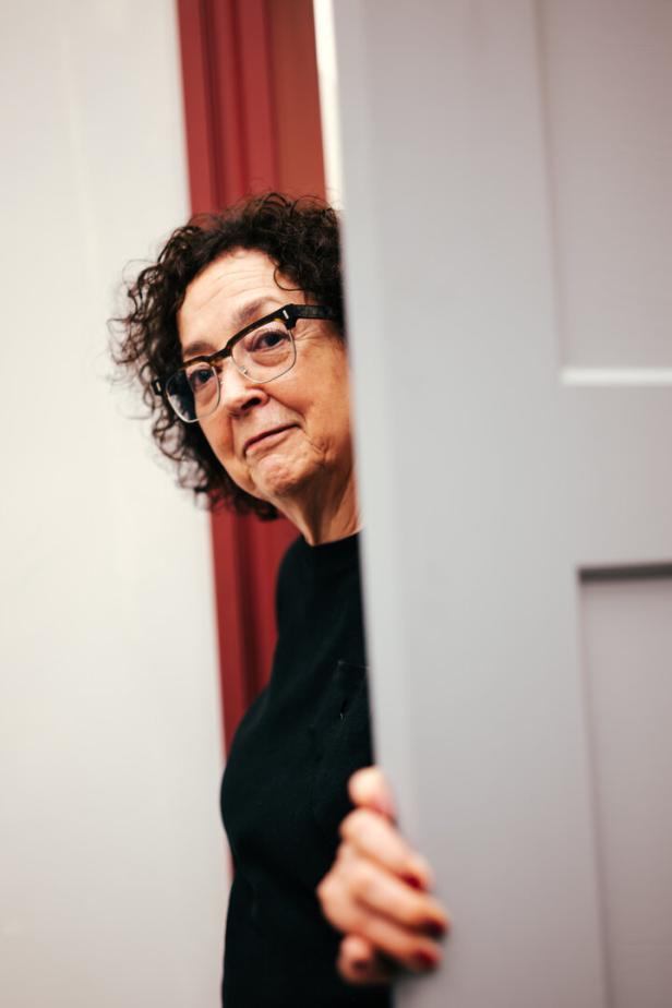 Die Künstlerin Anna Viebrock blickt verschmitzt durch einen Türspalt.