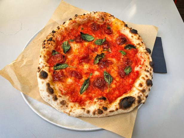 Das Bild zeigt eine mit Tomatenconfit und Basilikum belegte Pizza