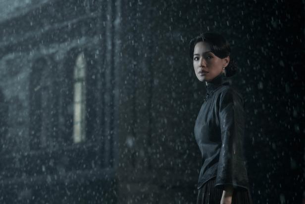 Der taiwanesische Filmstar Shu Qi in dunkler Kleidung vor einem grauen Haus