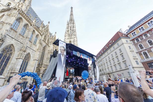 Eine Menschenmenge versammelt sich vor dem Wiener Stephansdom bei einem FPÖ-Volksfest mit einer großen Bühne und einem Porträt von Herbert Kickl.