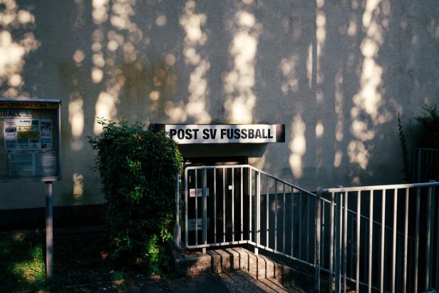 Ein Stiegengeländer, dahinter eine Türe, über der Türe die Aufschrift "Post SV Fussball"