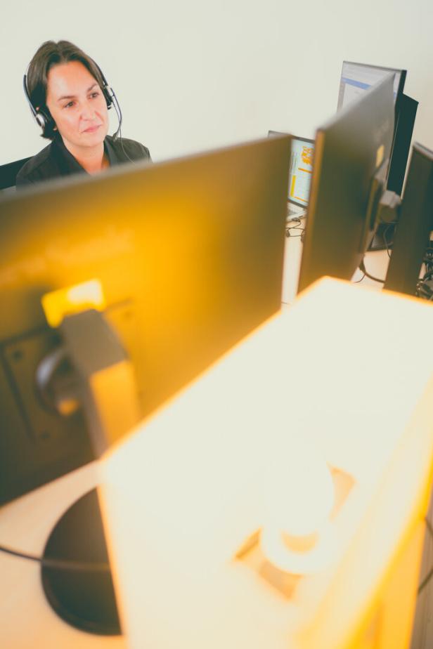 Frau mit Headset arbeitet an mehreren Monitoren im Büro.