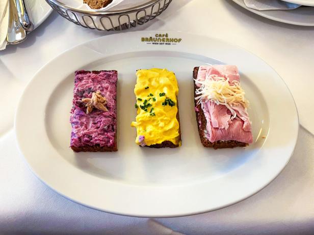 Drei belegte Brotscheiben auf einem Teller: links Rotkraut und Thunfisch, mittig Ei und Curry, rechts Schinken mit Kren.