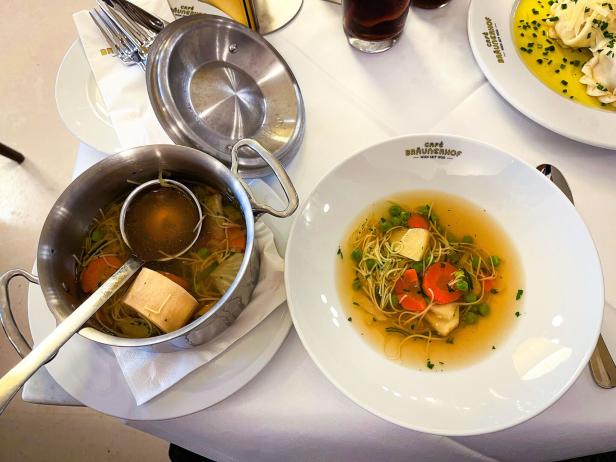 Auf einem Tisch stehen Suppen und eine Nudelsuppe mit Gemüse in Schalen und Töpfen