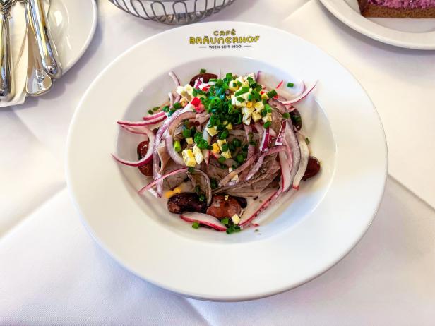 Teller mit Rindfleischsalat, roten Zwiebeln, Schnittlauch und Ei