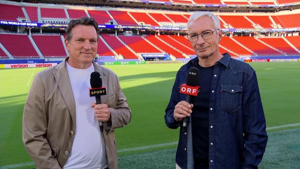 Andreas Herzog und Rainer Pariasek stehen mit Mikrofonen am Rand eines Fußballplatzes