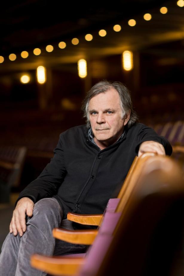 Markus Hinterhäuser, ehemaliger Intendant der Festspiele, in einem halbdunklen Theaterauditorium