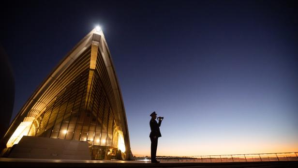 Das Bild zeigt einen einsamen Trompeter, der "The Last Post" auf den Stufen des Sydney Opera House spielt. Das Bild zeigt einen einsamen Trompeter, der "The Last Post" auf den Stufen des Sydney Opera House spielt.