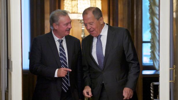 Zwei Männer in Anzügen unterhalten sich in einem Gebäude.