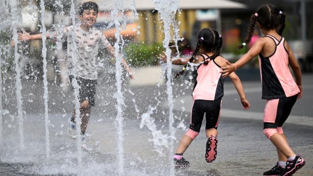 Kinder kühlen sich ein Wasserfontänen in einer Fußgängerzone in Wien