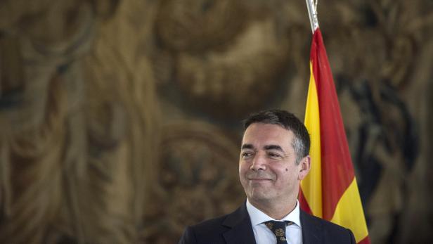 Ein Mann steht vor einer spanischen Flagge.