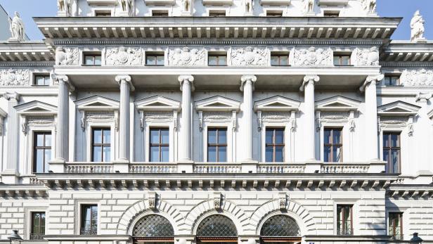 Die Fassade eines prunkvollen, weißen Gebäudes mit Statuen und Säulen.