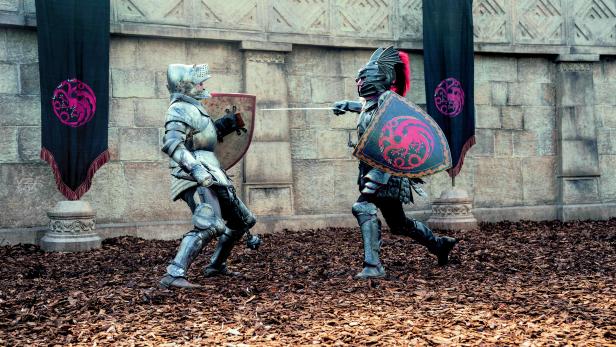 Zwei Ritter in Rüstung kämpfen mit Schwertern vor Bannern mit dem Targaryen-Drachen.