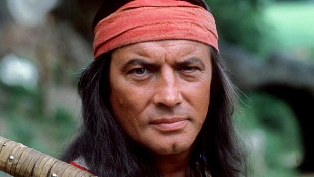 Pierre Brice als Winnetou mit Gewehr über der Schulter.