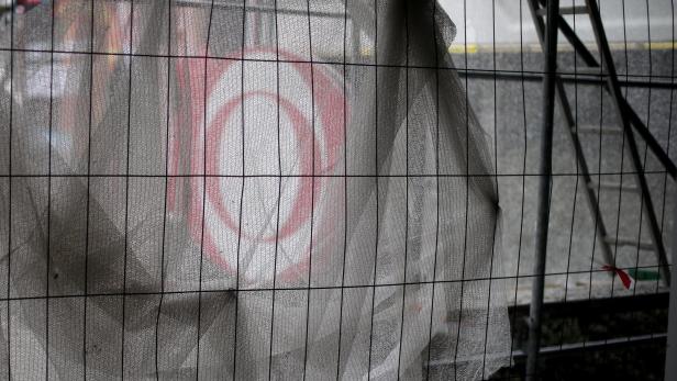 Ein Baustellenzaun mit einem teilweise verdeckten roten Kreis.