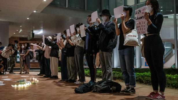 Demonstranten halten ein Schild und ein leeres Blatt Papier auf dem Campus der Universität Hongkong in Solidarität mit den Demonstrationen in Festlandchina gegen strenge Covid-Beschränkungen und für mehr Freiheiten fordern, in Hongkong, am 29. November 2022.