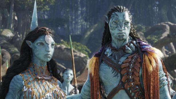Zwei Na'vi, ein Mann und eine Frau, stehen vor einem Wald in „Avatar: The Way of Water“.
