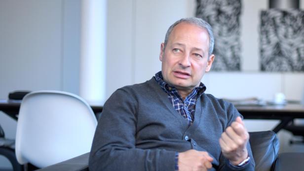 Ein Mann sitzt in einem Sessel und gestikuliert während eines Gesprächs.