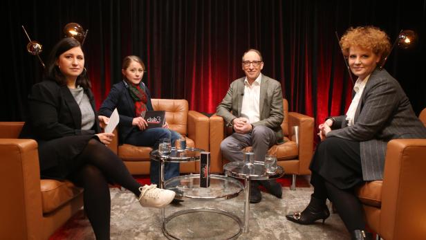 Vier Personen sitzen in Sesseln vor einem roten Vorhang für eine „Club 3“-Diskussion.