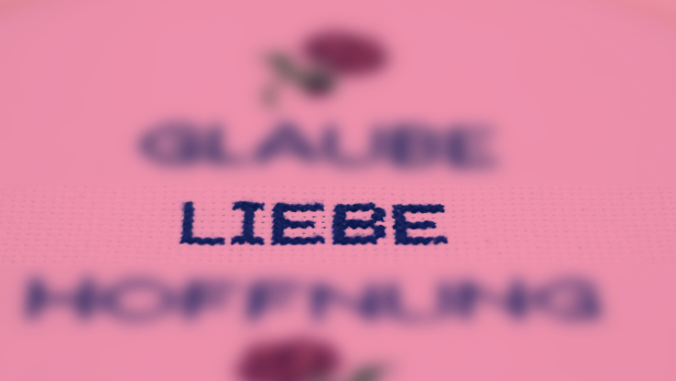 Ein rosa Stickrahmen mit den Worten Glaube, Liebe und Hoffnung.