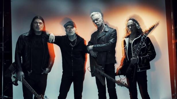 Die Band Metallica posiert mit ihren Instrumenten vor einem weißen Hintergrund.