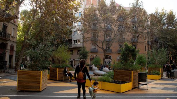 Eine Mutter geht mit ihrem Kind über einen Platz in der Stadt.