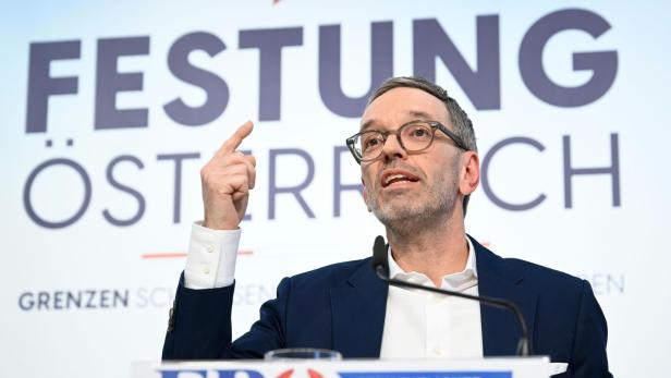 Ein Mann spricht vor einem Hintergrund mit der Aufschrift „Festung Österreich“ und dem FPÖ-Logo.