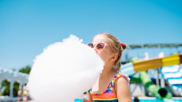 Ein Mädchen isst Zuckerwatte in einem Schwimmbad.