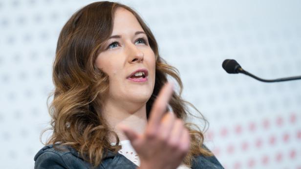 Eine Frau spricht vor einem Mikrofon und gestikuliert mit dem Finger.