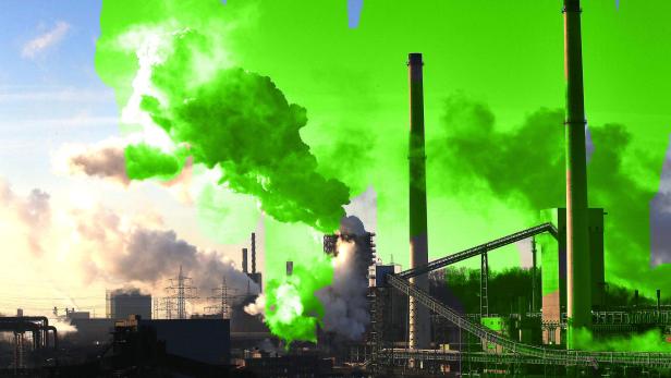 Eine Industrieanlage mit hohen Schornsteinen und Rauchentwicklung.