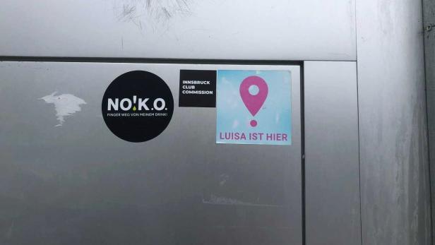 Man sieht die Tür eines Clubs in Tirol, auf der die Sticker der "Luisa-ist-hier"- Kampagne und der Sticker der Innsbruck Club Commission kleben