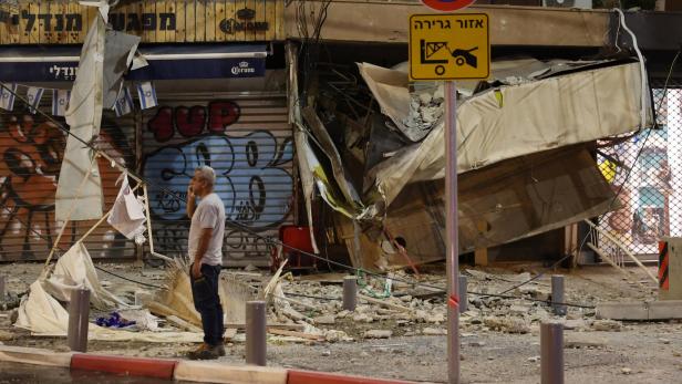 A man stands in front of a damaged shop in Tel Aviv, after it was hit by a rocket fired by Palestinian militants from the Gaza Strip on October 7, 2023. Palestinian militant group Hamas launched a surprise large-scale attack against Israel on October 7, firing thousands of rockets from Gaza and sending fighters to kill or abduct people as Israel retaliated with devastating air strikes. JACK GUEZ / AFP