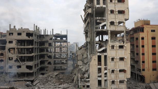 Zerstörte Gebäude ragen in einer Stadt unter einem bewölkten Himmel auf.
