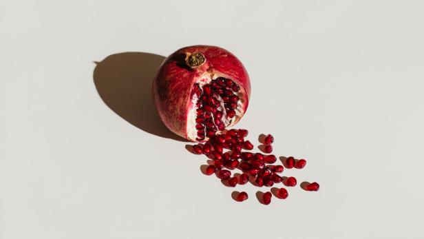 Ein aufgeschnittener Granatapfel mit herausgefallenen Kernen.