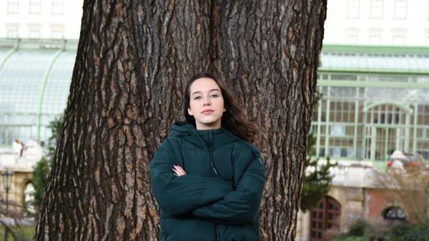 Eine junge Frau posiert vor einem Baum im Park.