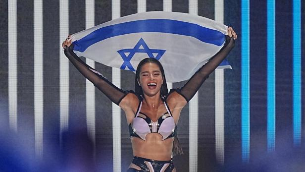 Eine Frau hält eine israelische Flagge hoch und lächelt.