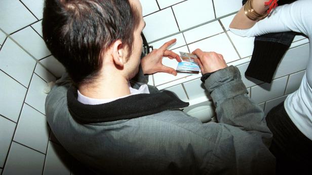 Zwei Personen konsumieren Drogen auf der Toilette.