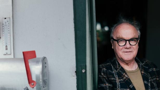 Ein Mann mit Brille und kariertem Sakko steht in einer Tür.