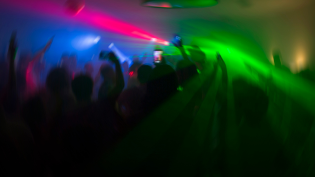 Menschenmenge tanzt in einem Club mit farbigen Lichtern.