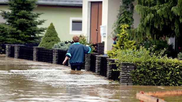 Eine Frau steht 2002 in Schwertberg bis zu den Oberschenkeln im Wasser vor ihrem Haus.