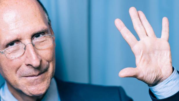 Peter Filzmaier in Anzug und Krawatte winkt in die Kamera.