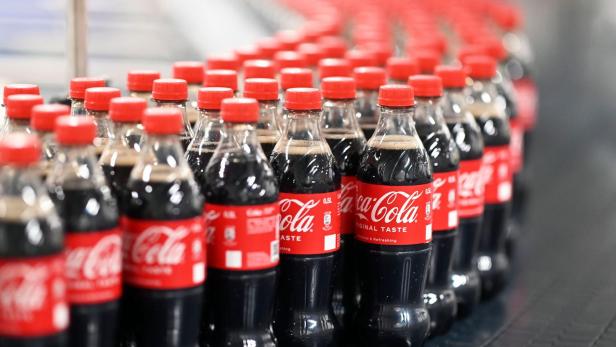 Viele Coca-Cola-Flaschen stehen auf einem Förderband.