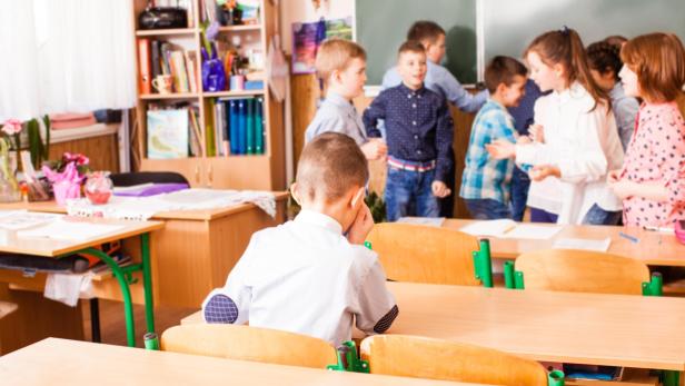 klasse_schule_kind_alleine_volksschule_ausschlus_mobbing Junge sitzt einsam in Klassenzimmer