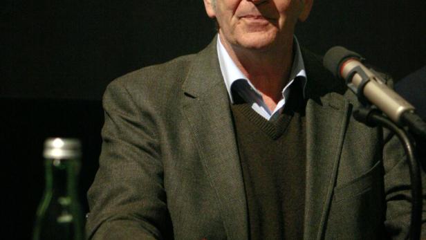 Harry Tomicek 2014 bei einem Vortrag im Wiener Filmmuseum Lächelnder Mann mittleren Alters vor einem Mikrofon, vor schwarzem Hintergrund