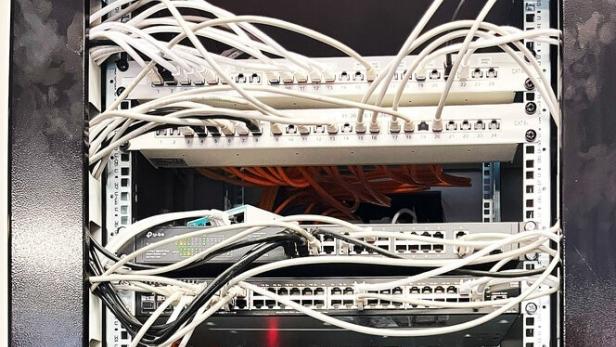 Die Internetquelle von Karosserie Puck. Viele weiße und schwarze Kabel winden sich durch das Bild und verbinden mehrere Internet-Router-Boxen.