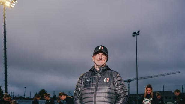 Fußball-Trainer Andreas Ogris steht auf dem Trainingsplatz des USV Neulengbach, im Hintergrund trainiert die Damenmannschaft